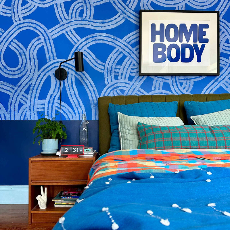 A pattern-filled bedroom with a wall sconce.