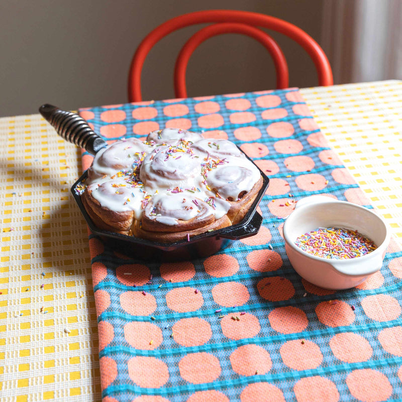 Confetti cinnamon rolls on an brightly patterned table with table cloth. 