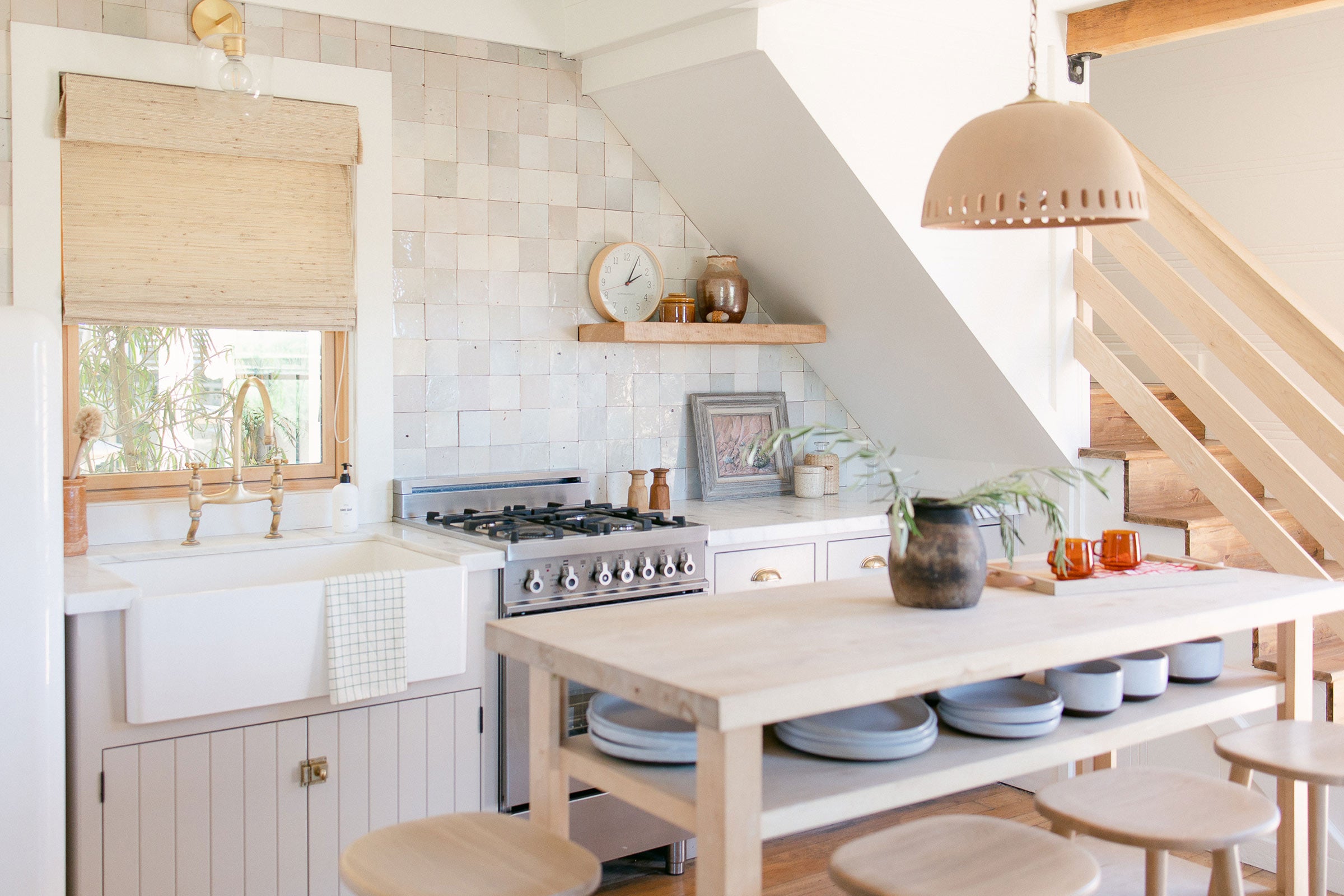 A bright kitchen with a ceramic pendant over a wooden table.